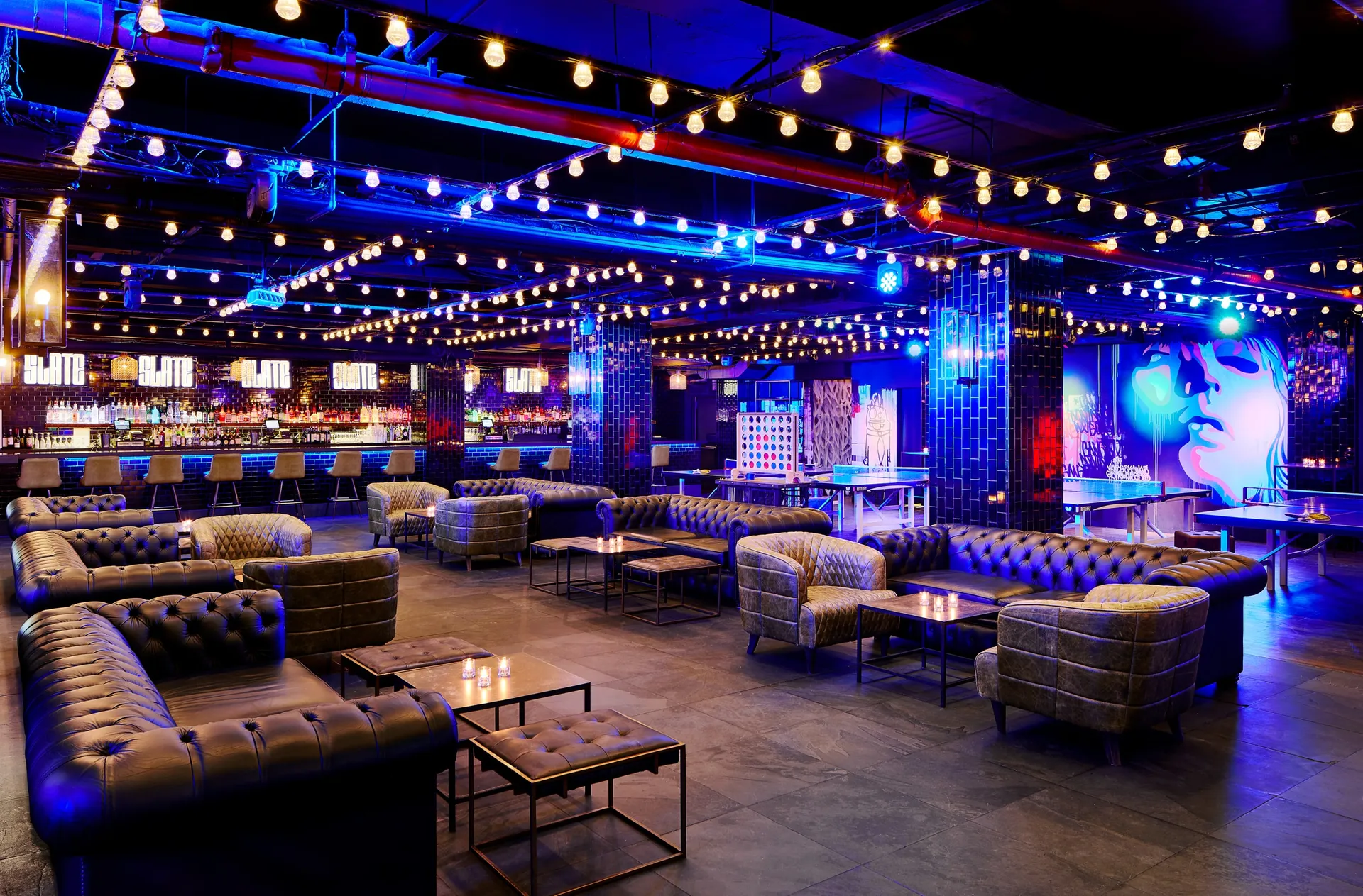 Slate NYC lounge with blue lights, booths, and string lights