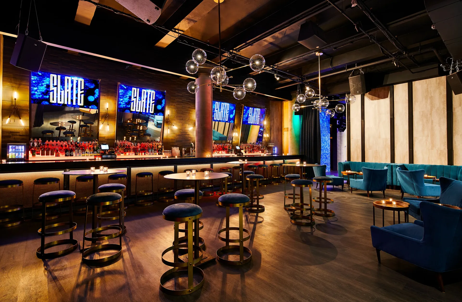 Slate NYC bar with illuminated screens, stools, and lounge seating
